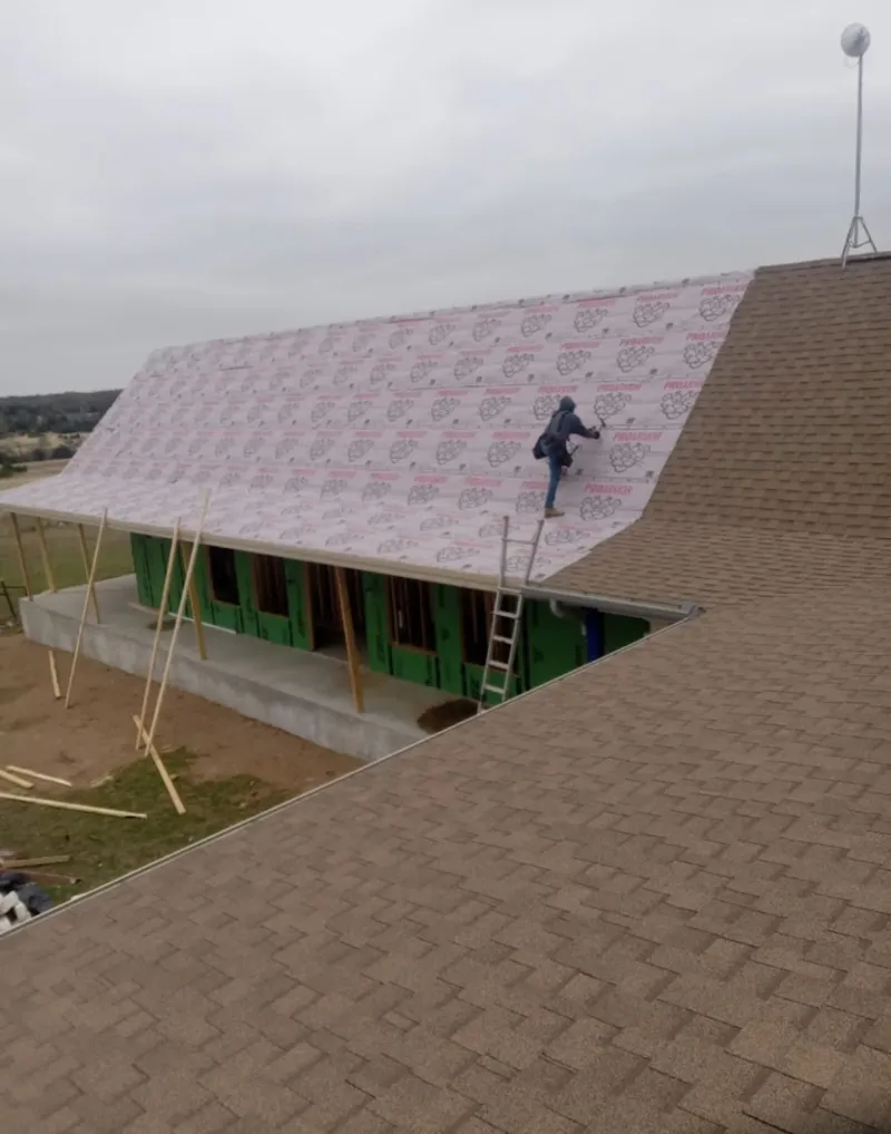 Worker preparing underlayment for a metal roof installation in Conroe